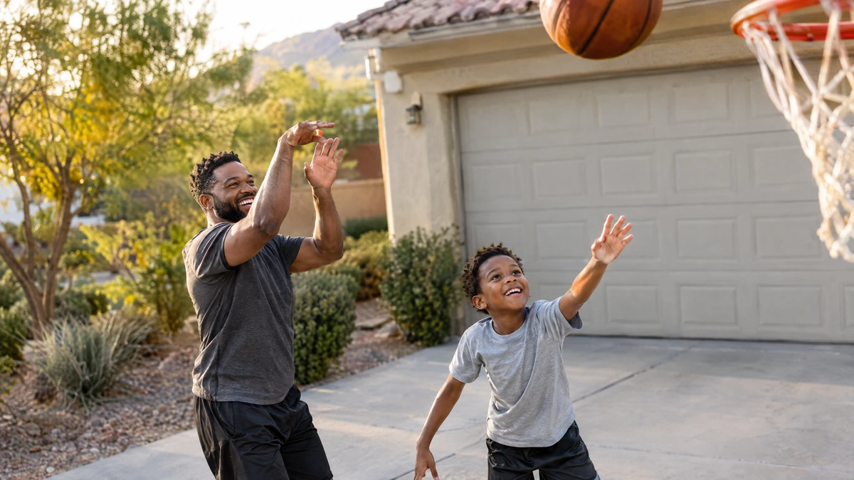 A father shoots hoops with his son in their driveway.